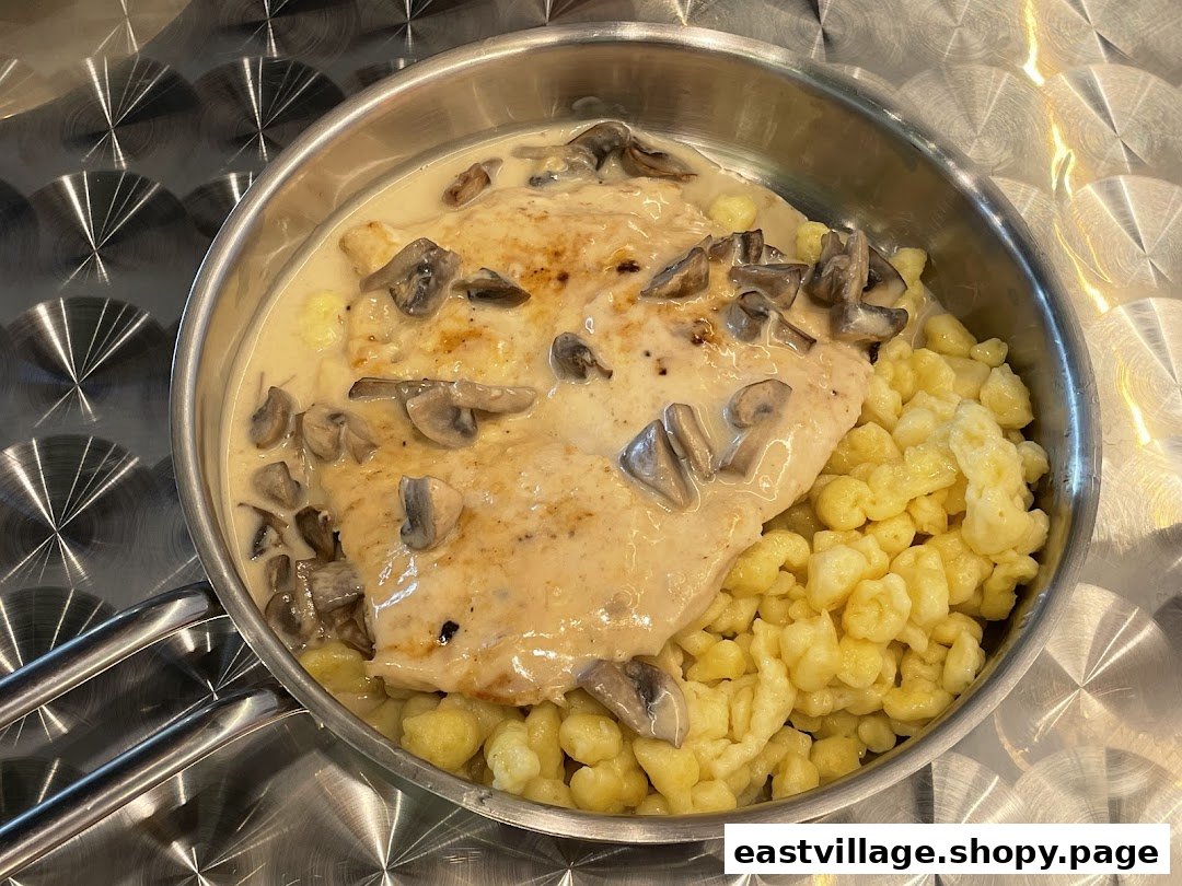 A delicious schnitzel with creamy mushroom sauce and spaetzle served in a metal pan.