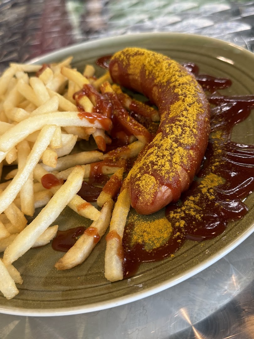 A plate of classic currywurst with golden fries, ketchup, and a generous dusting of curry powder.