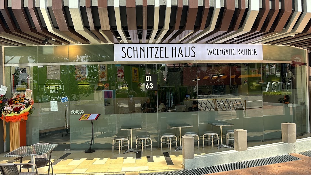 The storefront of Schnitzel Haus Wolfgang Ranner, featuring outdoor seating and a glass facade.