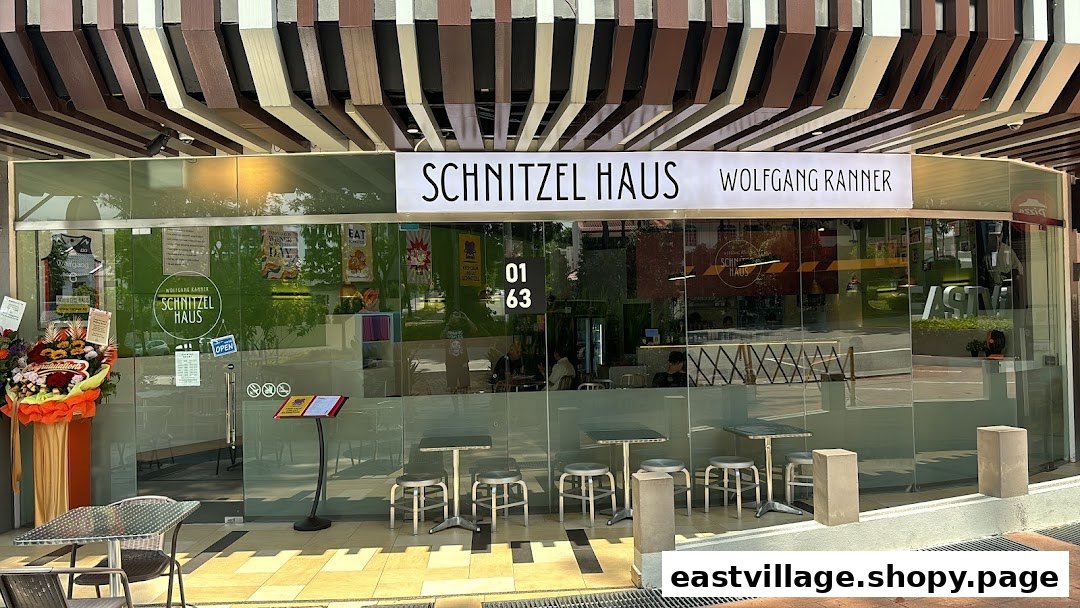The storefront of Schnitzel Haus Wolfgang Ranner, featuring outdoor seating and a glass facade.