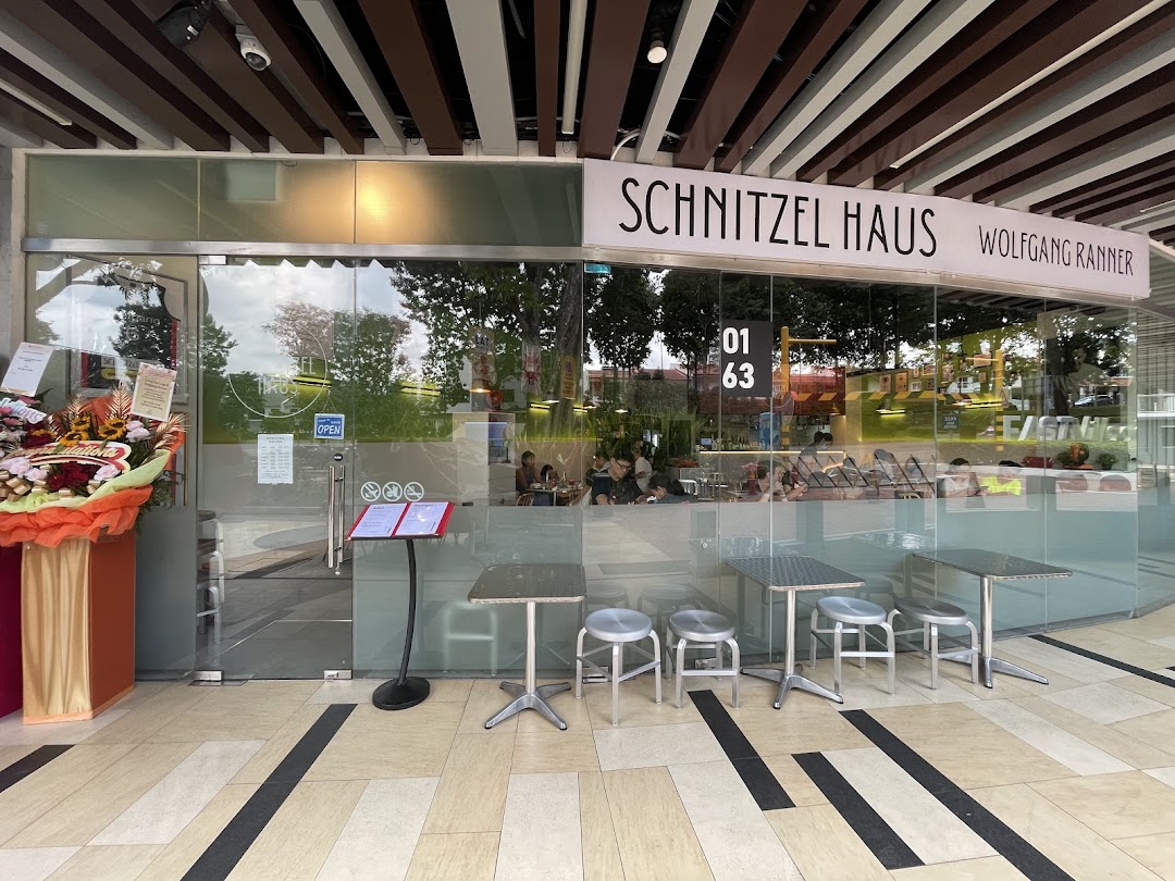 Exterior view of Schnitzel Haus Wolfgang Ranner, showcasing its glass facade and outdoor seating.