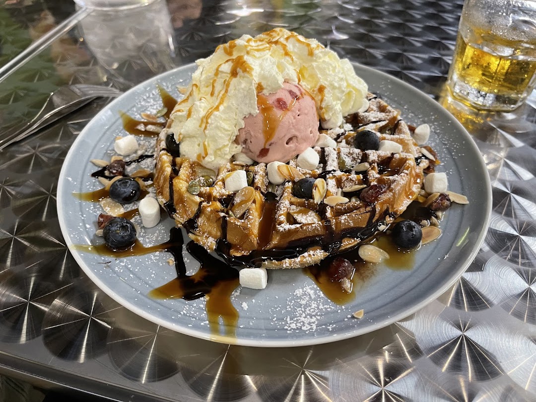 A delicious waffle topped with ice cream, whipped cream, berries, marshmallows, and syrup.