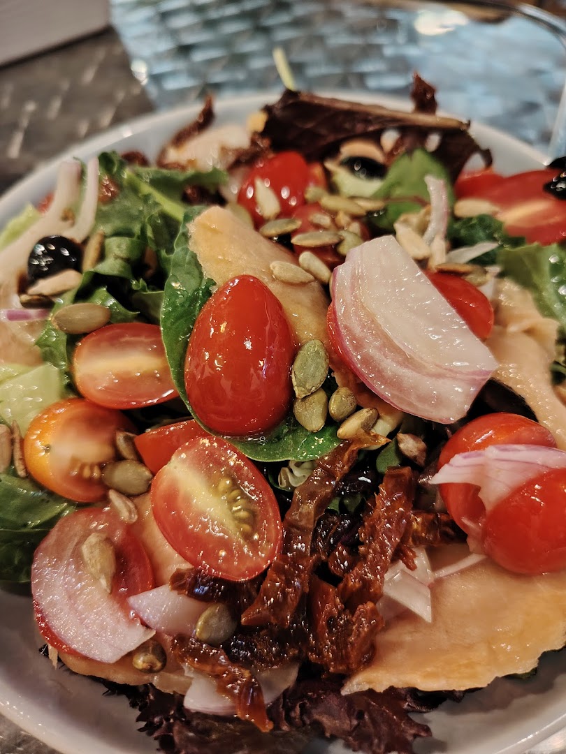 A vibrant close-up of a fresh salad featuring cherry tomatoes, red onion, pumpkin seeds, and greens.
