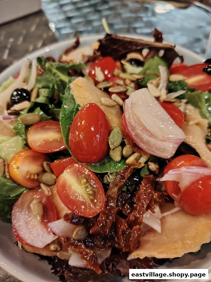 A vibrant close-up of a fresh salad featuring cherry tomatoes, red onion, pumpkin seeds, and greens.