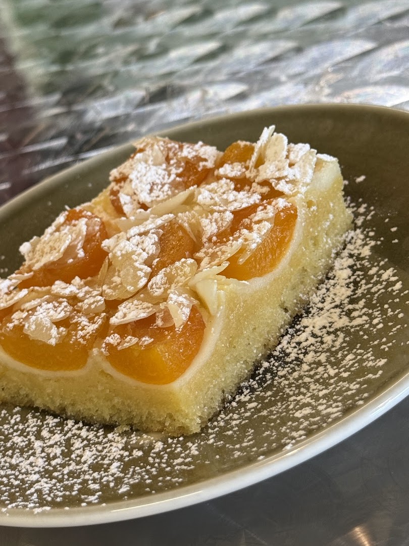 A delicious slice of apricot cake topped with powdered sugar and almond flakes.
