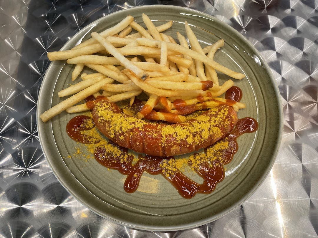 Delicious Currywurst with golden fries, ketchup, and curry powder on a plate.
