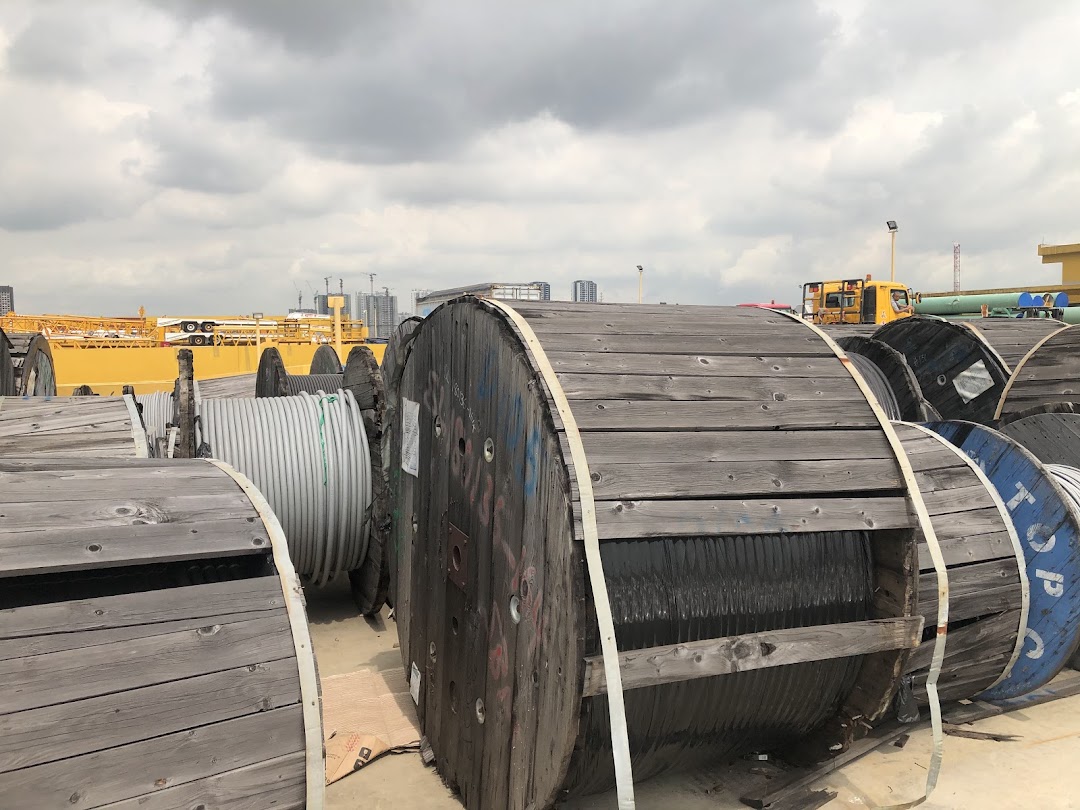 Large wooden spools of industrial cables and wires stored outdoors under a cloudy sky.