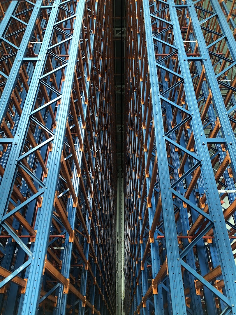 View of towering blue and orange industrial storage racks in a large warehouse.