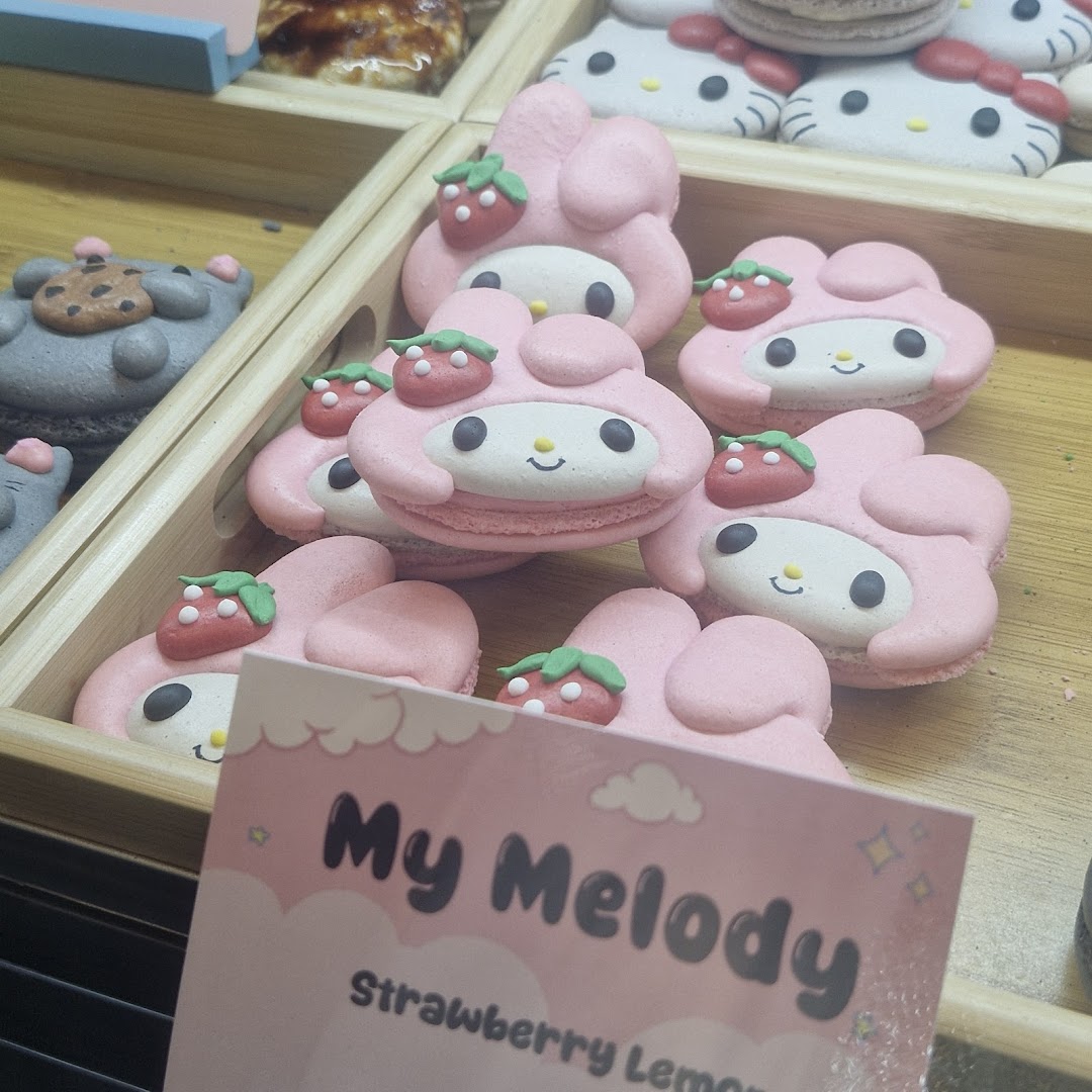 Close-up of adorable pink My Melody character macarons with strawberry decorations in a display case.