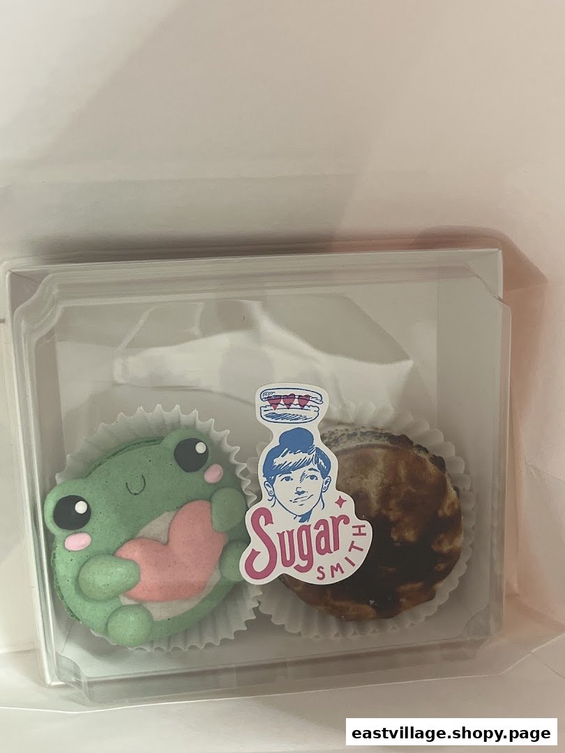 Two delightful pastries, including a frog-shaped macaron, in a clear box from Sugarsmith.