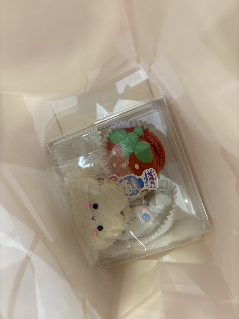 A clear box of adorable, character-shaped macarons from Sugarsmith, nestled in a light pink bag.