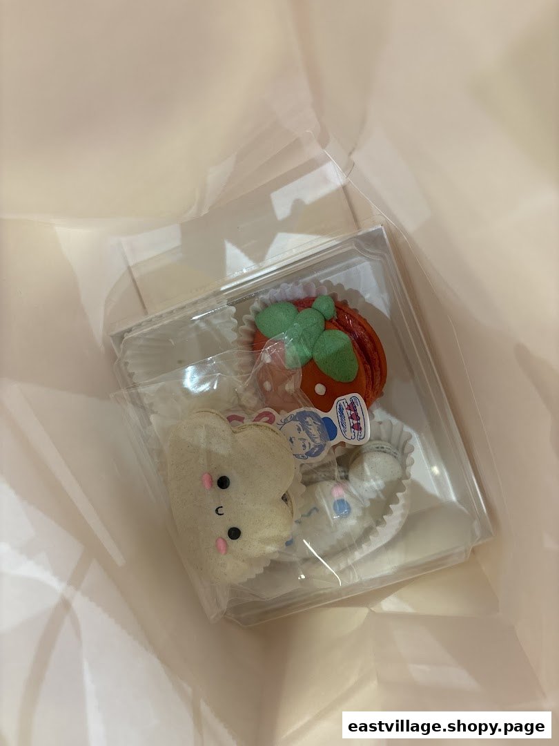 A clear box of adorable, character-shaped macarons from Sugarsmith, nestled in a light pink bag.