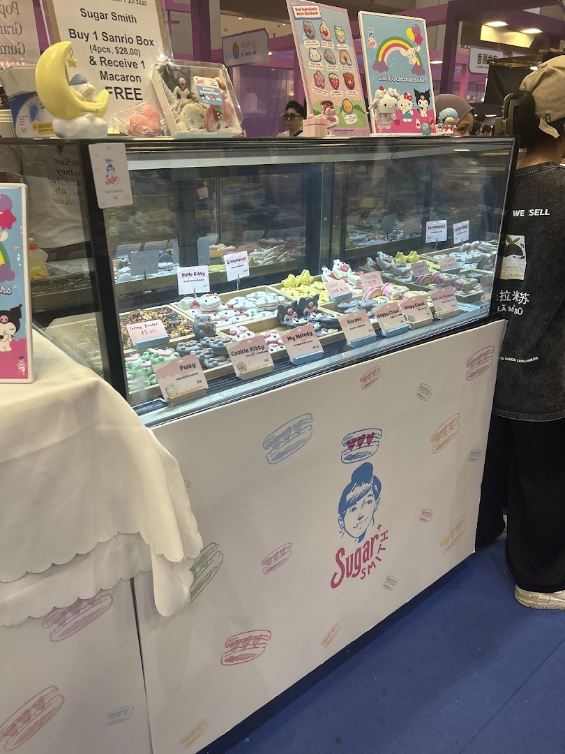 A vibrant display case at Sugarsmith showcasing an array of colorful, character-themed macarons and cookies.