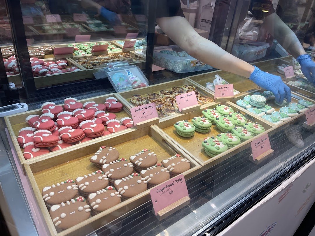 A vibrant display case at Sugarsmith filled with festive macarons and decorated cookies.