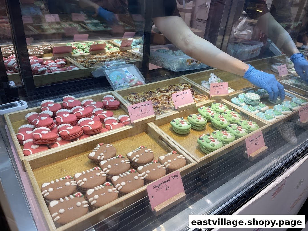 A vibrant display case at Sugarsmith filled with festive macarons and decorated cookies.