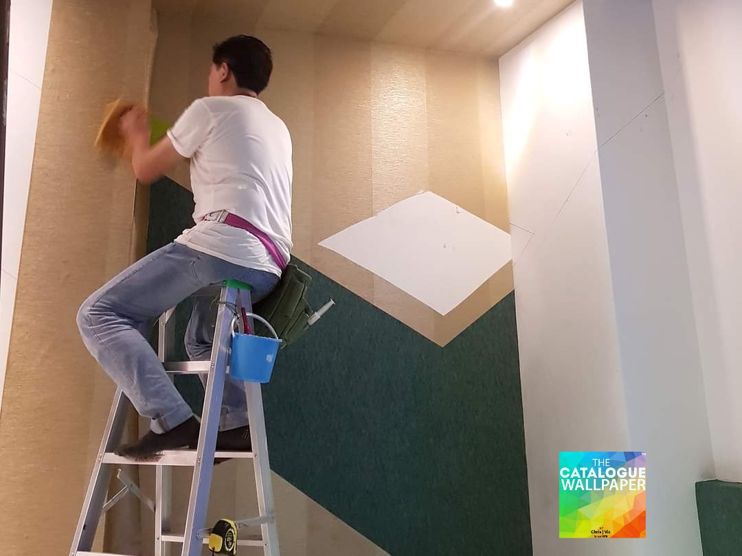 A skilled professional installing geometric wallpaper, showcasing the shop's expertise.