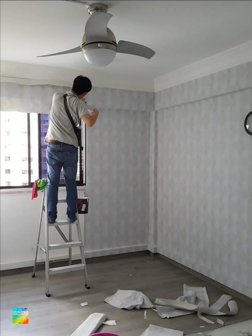 A professional installs patterned wallpaper in a room, showcasing the gallery's home improvement services.