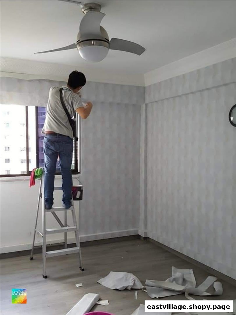 A professional installs patterned wallpaper in a room, showcasing the gallery's home improvement services.