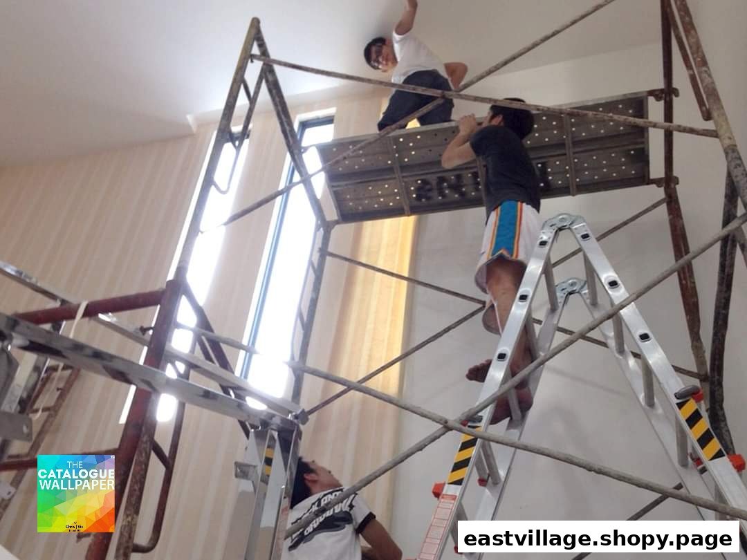 Workers on scaffolding and ladders installing wallpaper or working on a ceiling in a room.