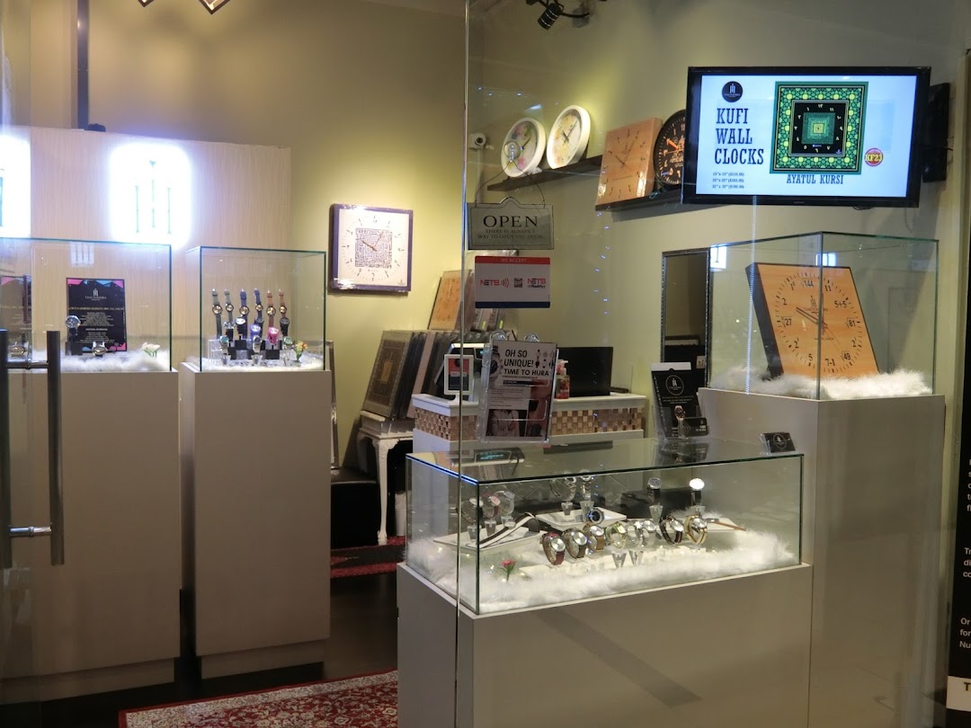 Interior view of Time To Hijra, showcasing display cases with watches and unique Kufi wall clocks.