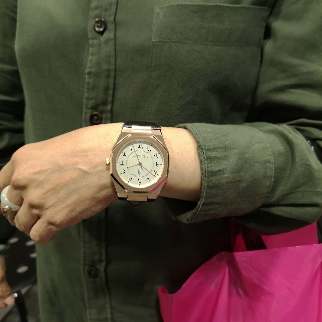 A person wearing a stylish watch with Arabic numerals, showcasing the unique design of the timepiece.