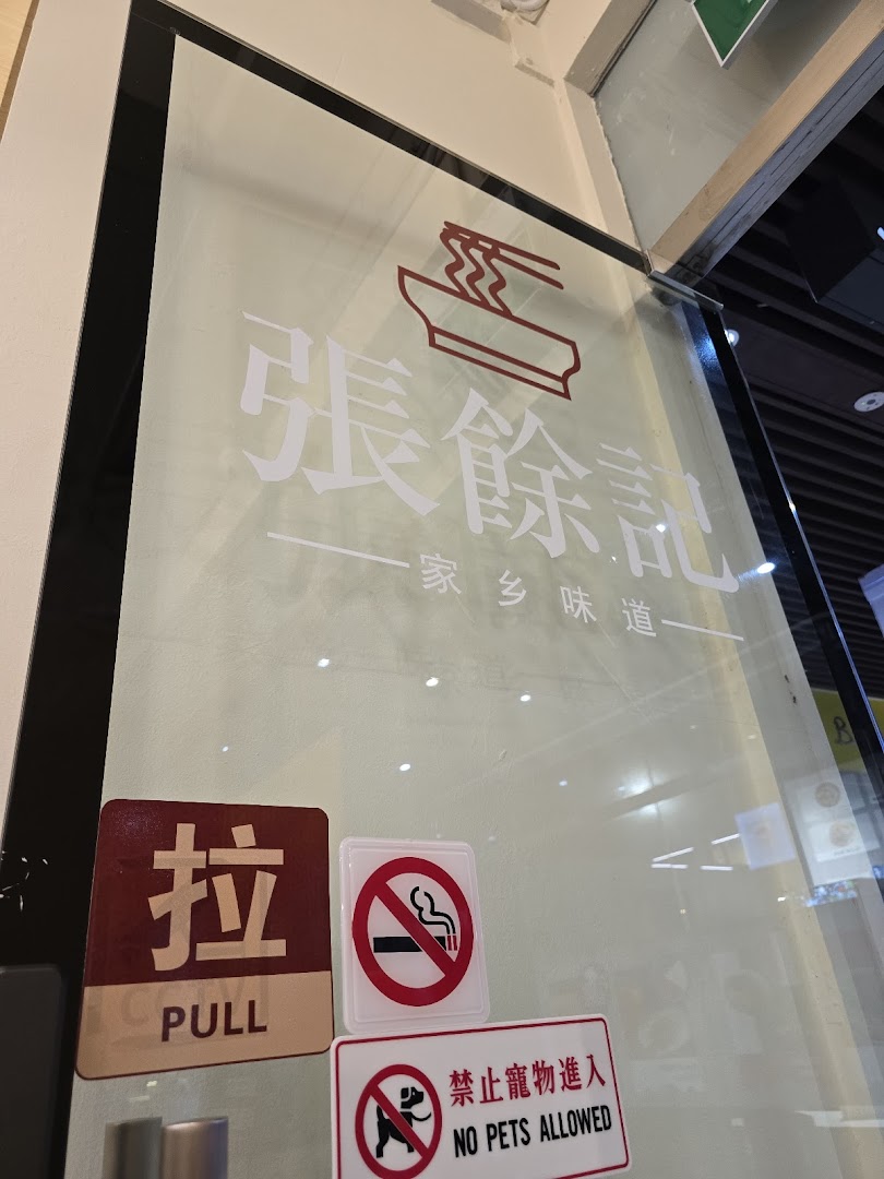 The glass entrance of '張餘記' (Zhang Yu Ji) featuring its noodle bowl logo and 'Hometown Flavor' tagline.