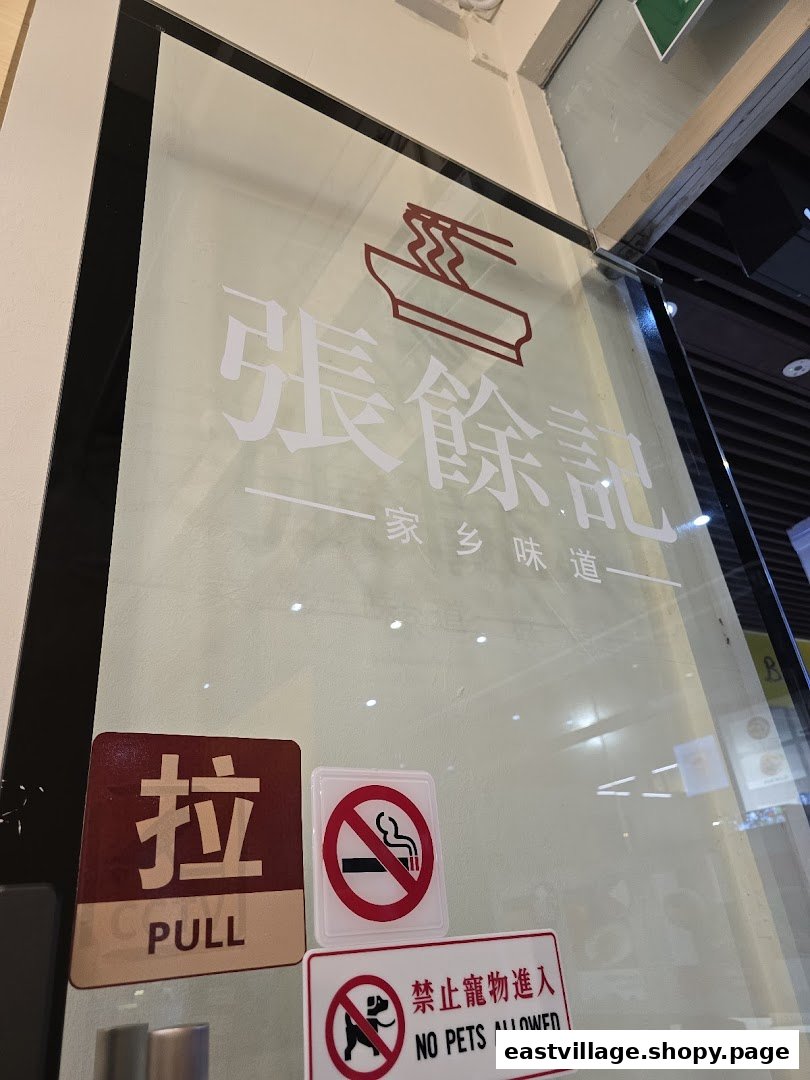 The glass entrance of '張餘記' (Zhang Yu Ji) featuring its noodle bowl logo and 'Hometown Flavor' tagline.