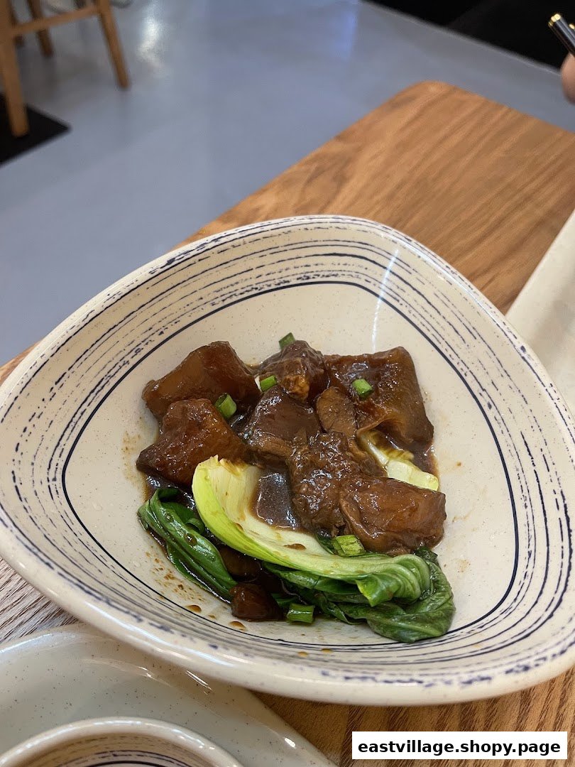 A close-up of a delicious braised meat dish with green vegetables served in a patterned bowl.