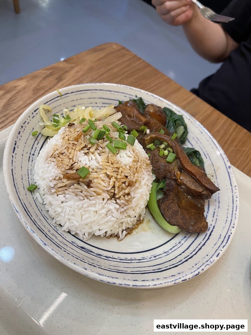 A plate of braised meat with rice and vegetables, garnished with spring onions, from 張餘記.