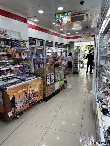 Interior view of a 7-Eleven store with aisles and refrigerators.