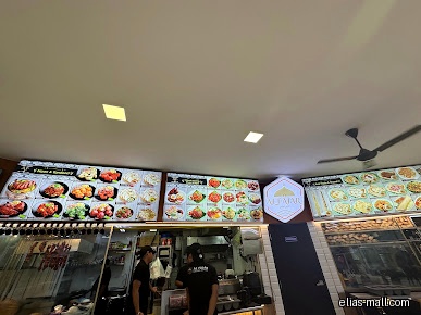 Restaurant interior with menu boards, staff, and kitchen visible.