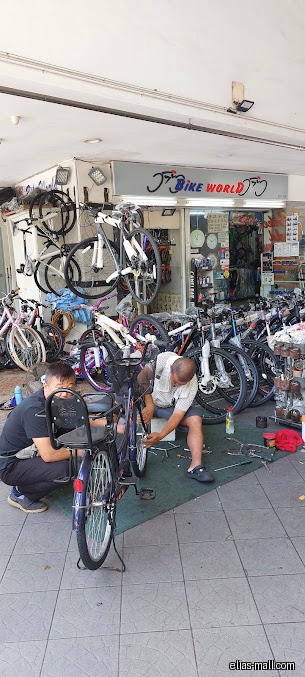 Bike World shop front with mechanics repairing bicycles outside the store.