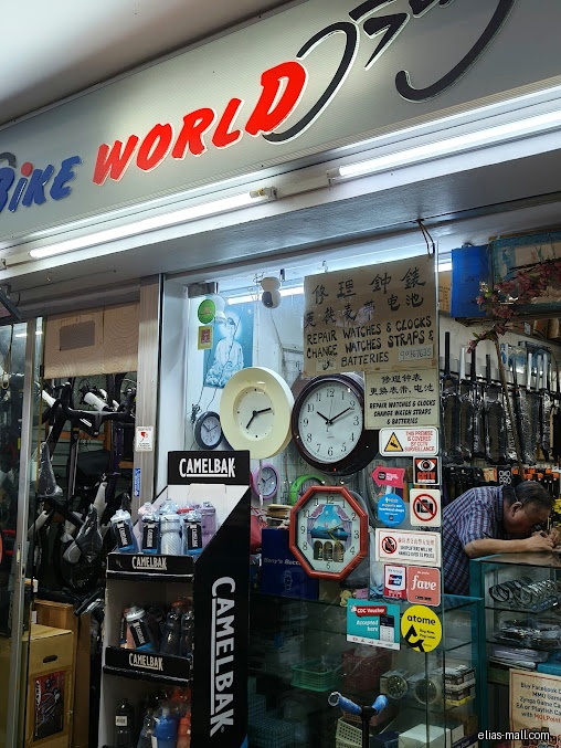 Bike World shop front with clocks, Camelbak products, and a repair sign.