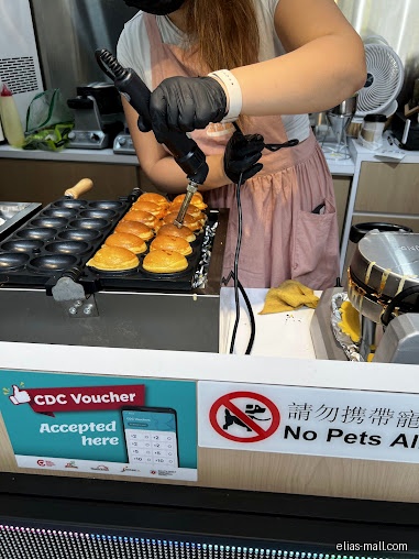 A person in black gloves prepares small, round breads on a griddle.