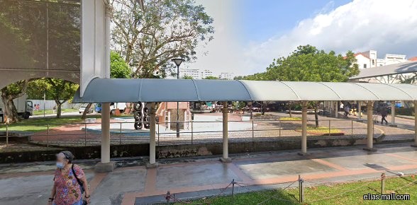 The image shows a covered walkway leading to a playground area.