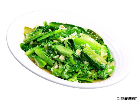 A white plate holds stir-fried green vegetables with garlic.