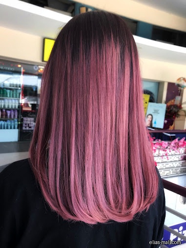 A woman with long, straight, dark brown to pink ombre hair.