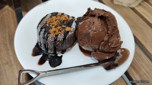 A chocolate lava cake with ice cream on a white plate.