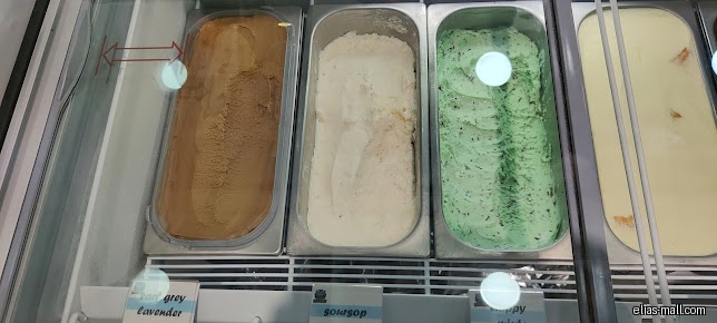 A display case shows different flavors of ice cream, including mint and lavender.