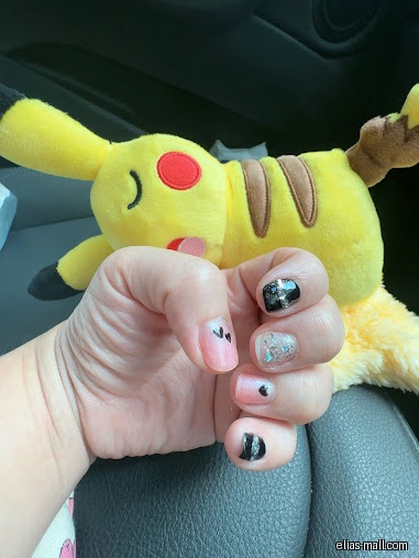 A hand with painted nails is shown with a Pikachu plush toy.