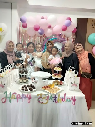 People pose behind a table with food and a Happy Birthday banner.
