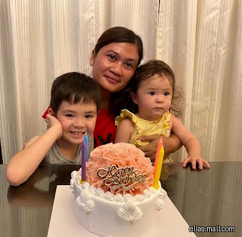 A woman and two children pose with a birthday cake.