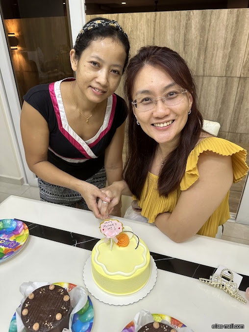 Two women cutting a cake with a 'Happy Mother's Day' topper.