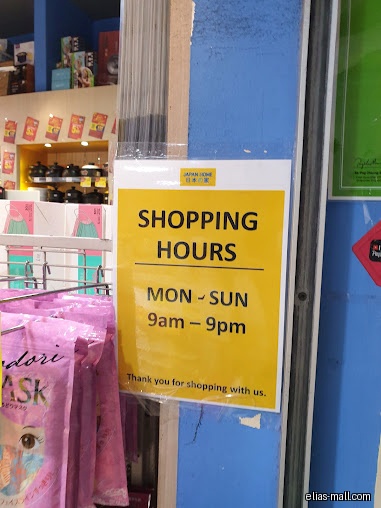 Japan Home's shopping hours sign is posted on a blue wall, next to products.