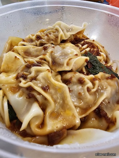 A close-up shot of dumplings with sauce in a plastic bowl.
