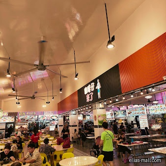 The image shows the interior of a food court with many people eating.
