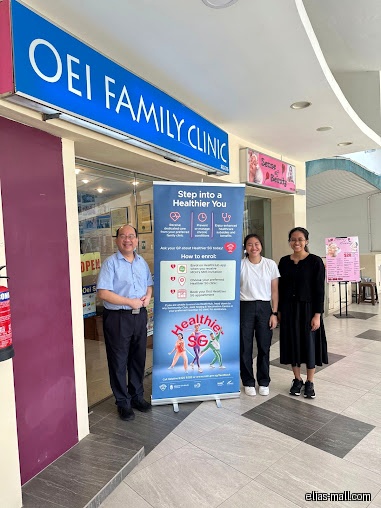Oei Family Clinic shop front with staff and a promotional banner.