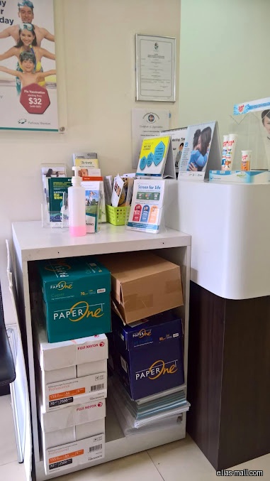 The image shows a shelf with paper, brochures, and a hand sanitizer.