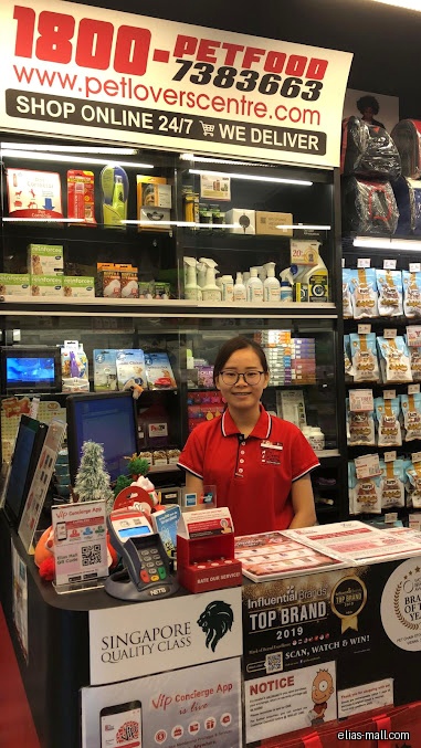 A Pet Lovers Centre employee stands behind a counter with products displayed.