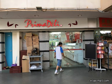 PrimaDéli shop front with a man walking inside and boxes outside.